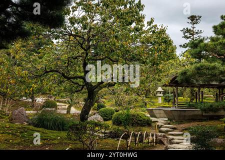 Une vue paisible et tranquille sur un beau jardin avec une verdure luxuriante, des fleurs colorées et des chemins sinueux en pierre Banque D'Images