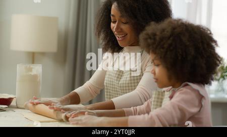 Famille heureuse à la cuisine cuisiner ensemble souriant maman afro-américaine femme mère sale visage dans la farine blanche enseignant mignon enfant fille préscolaire Banque D'Images