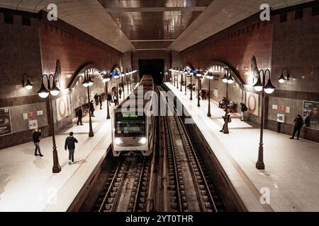 Station de métro Lavov Most à Sofia, Bulgarie, un train arrivant à la plate-forme, éclairé par des lampes de style vintage et entouré de navetteurs. Banque D'Images