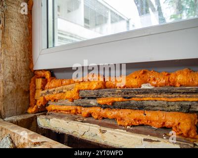 Mettre de vieilles planches sous la fenêtre lors de son installation pour réduire la consommation de mousse de montage Banque D'Images
