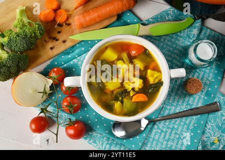 Soupe de légumes avec épeautre dans un bol en céramique blanche, avec quelques ingrédients autour Banque D'Images