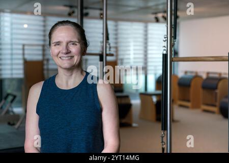 Femme d'âge moyen posant fièrement dans le gymnase de Pilates. Banque D'Images