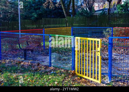 Un bac à sable vide pour enfants clôturé avec une clôture colorée et lumineuse. Ouvrez la porte. Banque D'Images