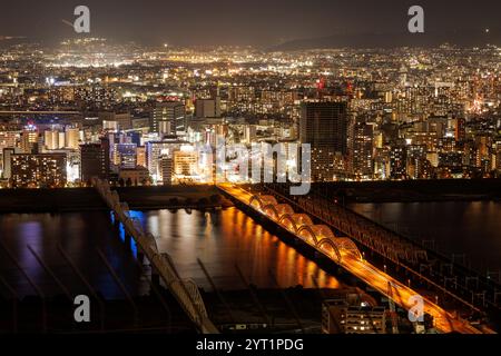 Une vue aérienne époustouflante d'une ville animée d'Osaka la nuit, avec des lumières éblouissantes se reflétant magnifiquement sur l'eau Banque D'Images