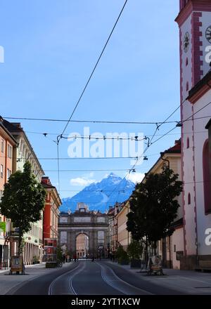 Innsbruck, Autriche - septembre 29 2024 : vue imprenable sur l'Arc de Triomphe sur Maria-Theresien-Strasse encadrée par l'architecture colorée et les Alpes Banque D'Images