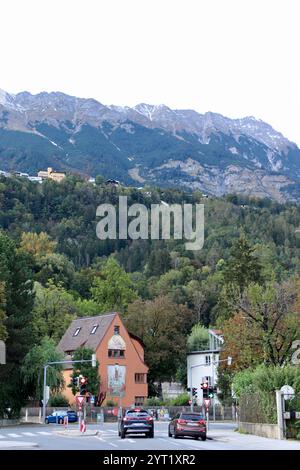 Innsbruck, Autriche - septembre 30 2024 : City Street à Innsbruck avec bâtiment coloré, vue sur la montagne et voitures à l'intersection des feux de circulation Banque D'Images