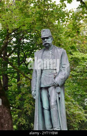 Innsbruck, Autriche - septembre 30 2024 : Statue de bronze de l'empereur François-Joseph Ier en uniforme militaire et pardessus, face aux arbres verts dans le parc Banque D'Images