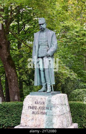 Innsbruck, Autriche - septembre 30 2024 : Statue de bronze de l'empereur François-Joseph Ier en uniforme militaire et pardessus, face aux arbres verts dans le parc Banque D'Images