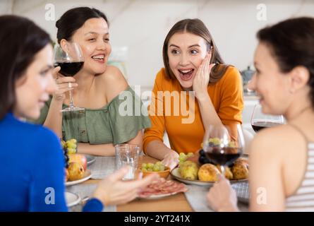 Des femmes heureuses se sont rassemblées autour d'une table festive ; participant à des discussions animées et appréciant les délices du vin Banque D'Images