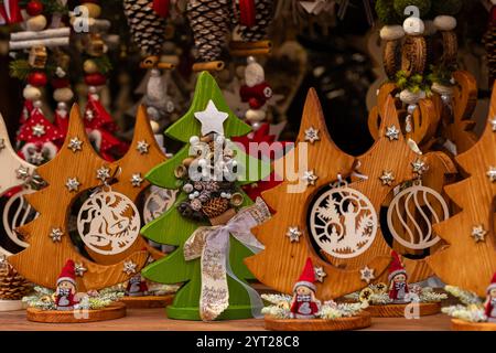 Gros plan de décorations de Noël en bois fabriquées à la main avec des motifs festifs, y compris de petits arbres, des étoiles et des figurines sur un étal de marché Banque D'Images