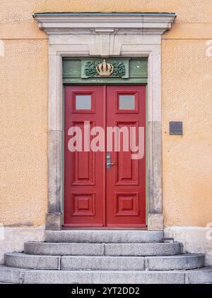 Stockholm, Suède - 26 février 2023 : majestueuses portes doubles rouges ornées de vitres et d'une couronne décorative au-dessus Banque D'Images