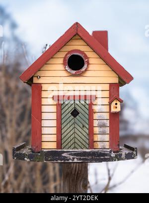 Stockholm, Suède - 26 février 2023 : gros plan d'un nichoir rouge et jaune attirant les yeux des marcheurs dans un paysage hivernal légèrement enneigé Banque D'Images