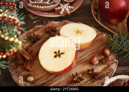 Pomme rouge coupée en deux avec une étoile au milieu avec cannelle, anis étoilé, noisettes et décoration de Noël Banque D'Images