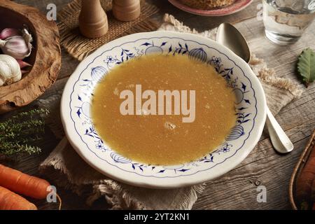 Bouillon d'os de poulet dans une assiette blanche avec des ornements bleus sur une table en bois Banque D'Images