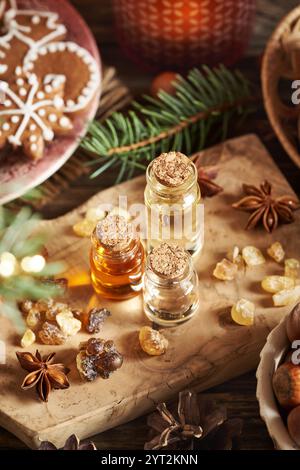 Trois bouteilles transparentes d'huiles essentielles d'aromathérapie avec résine d'encens, sapin et décoration de Noël Banque D'Images