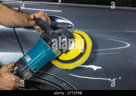 Détaillant de voiture professionnel tient la ponceuse orbitale aléatoire à air ou le polisseur à double action dans la main tout en polissant la surface de peinture de la peinture gris brillant. Voiture d Banque D'Images