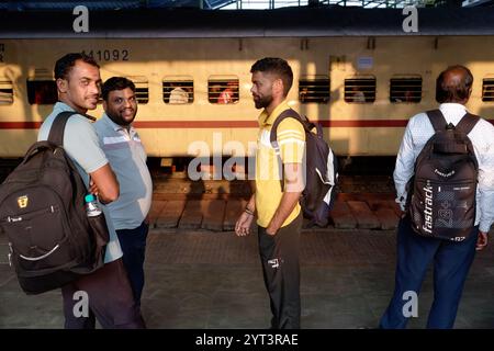 Voyageurs de chemin de fer masculins attendant un train de banlieue de la Central Line, debout sur un quai à la gare de Dadar à Mumbai, en Inde Banque D'Images