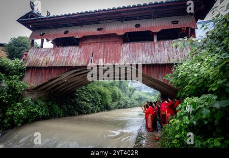 (241206) -- PÉKIN, 6 décembre 2024 (Xinhua) -- les villageois participent à une activité folklorique traditionnelle du Festival de Duanwu, ou Festival des bateaux-dragons, au pont Shuangmen, un pont en arc de bois, dans le comté de Qingyuan de la ville de Lishui, province du Zhejiang, dans l'est de la Chine, 11 juin 2024. Trois éléments culturels chinois, à savoir les techniques textiles traditionnelles Li : filature, teinture, tissage et broderie, fête du nouvel an de Qiang, célébrée dans la province chinoise du Sichuan, et la conception et les pratiques traditionnelles pour la construction de ponts en arc de bois chinois, ont été ajoutés par l'UNESCO à sa liste représentative de l'Intangib Banque D'Images