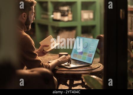 Jeune homme d'affaires analysant les métriques commerciales et le tableau de bord KPI sur ordinateur portable dans un café branché. Visualisation et performance des données par un professionnel moderne Banque D'Images