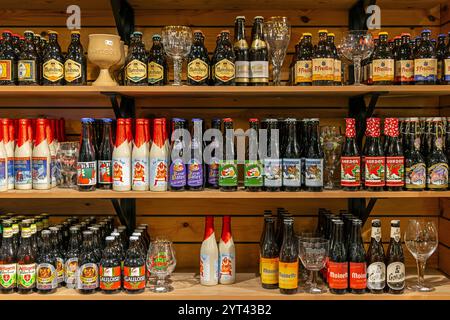 Collection de bières belges avec bouteilles et verres dans une boutique de souvenirs, Bruges, Belgique. Banque D'Images