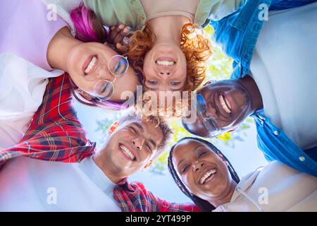 Groupe diversifié d'amis souriant dans un cercle en plein air Banque D'Images