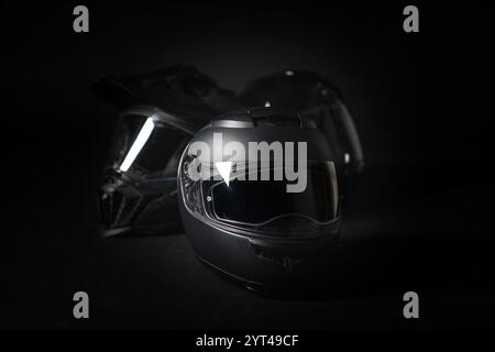 Casque de moto noir sur fond noir. Banque D'Images