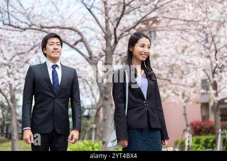 Homme et femme debout sous une rangée de cerisiers en fleurs Banque D'Images