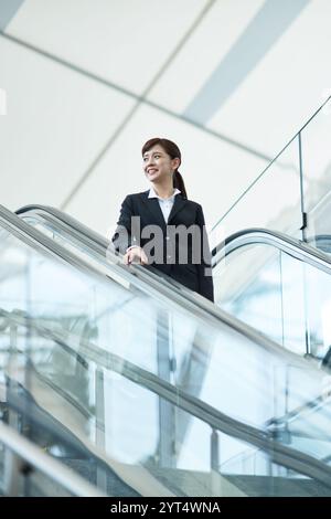 Femme d'affaires chevauchant l'escalator Banque D'Images