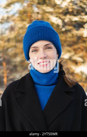 Heureuse jeune femme adulte souriant dans la forêt d'hiver Banque D'Images