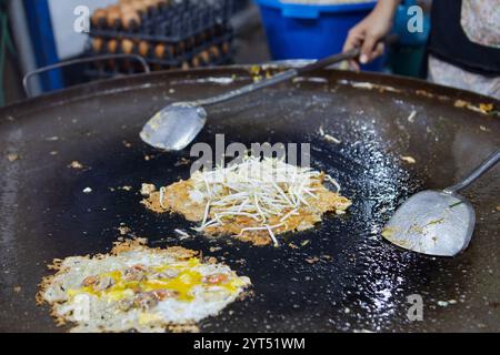 Chef préparant la moule frite avec l'oeuf dans la poêle à frire au marché de rue Banque D'Images