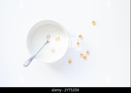 Bol de lait avec trois céréales cheerios sur fond blanc. Banque D'Images