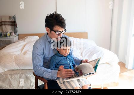 Parent et enfant se lisant une histoire l'un à l'autre dans leur chambre Banque D'Images