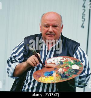 Konrad Kujau, deutscher Maler, Kunstfälscher und Aktionskünstler, bekannt wurde er im Jahr 1983 als Fälscher der Hitler-Tagebücher, die er dem politischen Wochenmagazin Stern verkaufte, Portrait mit Malpalette, Deutschland, vers 1990. Konrad Kujau, peintre allemand, faussaire d'art et artiste d'action, il se fait connaître en 1983 comme le faussaire des journaux intimes hitlériens, qu'il vend à l'hebdomadaire politique Stern, portrait avec palette de peinture, Allemagne, vers 1990. Banque D'Images