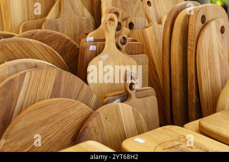 Un assortiment vibrant de planches à découper en bois artisanales et de plateaux de service est présenté sur un marché local. Les tons chauds du bois soulignent th Banque D'Images