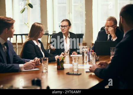Professionnels des affaires participant activement à la séance de brainstorming animée par un gestionnaire âgé autour de la table de conférence Banque D'Images