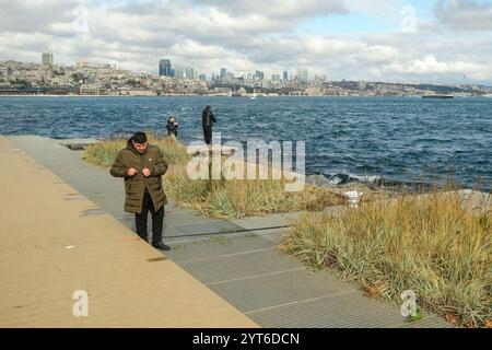 Istanbul, Turquie. 5 décembre 2024. Un homme préparant son équipement de pêche tandis que d'autres pêchent en arrière-plan. On a vu des pêcheurs amateurs pêcher avec des cannes à pêche sur les rives du Bosphore. (Crédit image : © mine TOZ/SOPA images via ZUMA Press Wire/Alamy Live News) USAGE ÉDITORIAL SEULEMENT! Non destiné à UN USAGE commercial ! Banque D'Images