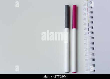 Stylo marqueur de couleur et carnet de papier spirale sur fond blanc avec espace pour la copie. Papeterie créative, écriture à la main, fournitures de bureau, rentrée scolaire Banque D'Images