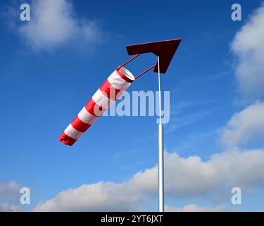une chaussette rayée rouge et blanche avec une flèche directionnelle dans le ciel bleu Banque D'Images