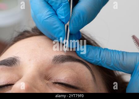 Esthéticienne modelant les sourcils de la cliente lors d'une procédure de correction des sourcils en salon de beauté Banque D'Images