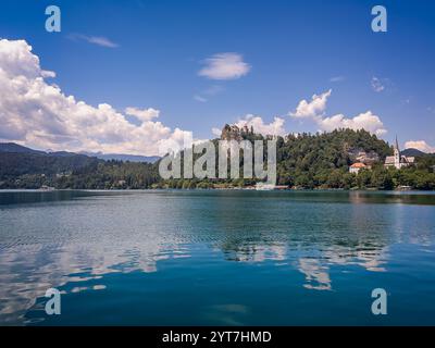 Lac de Bled, Slovénie - 28 juin 2024 : large paysage au-dessus de l'eau du lac avec le château sur son rocher au milieu et l'église Martin sur le Banque D'Images