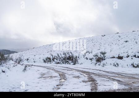 une route de montagne un jour d'hiver avec des traces de pneus dans la neige, des marques de roue sur une route enneigée Banque D'Images