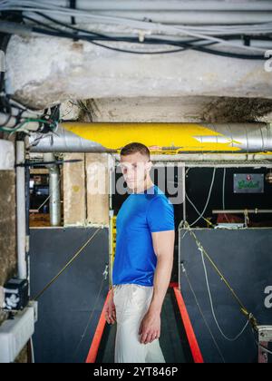 Homme avec T-shirt bleu dans la pièce du sous-sol Banque D'Images