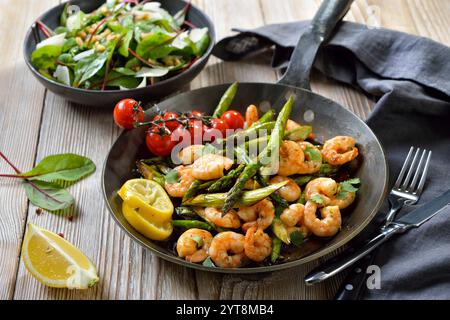 Asperges vertes frites aux crevettes et à la coriandre fraîche servies avec salade de bards au parmesan et aux noix Banque D'Images