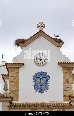 Une cigogne blanche (Ciconia ciconia) sur son nid sur le toit d'une église à Olhao, Algarve, Portugal. Banque D'Images