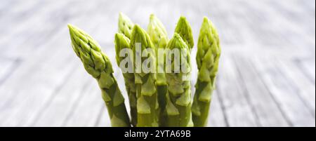 Bouts d'asperges vertes fraîches sur des planches de bois gris rustique. Gros plan avec une courte profondeur de champ. Contexte pour une gastronomie saine avec espace pour le texte. Banque D'Images