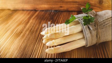 Bouquet d'asperges blanches fraîches. Légumes de saison de printemps sur bois rustik. Scène de cuisine ensoleillée pour un concept gastronomique sain avec espace pour le texte. Banque D'Images