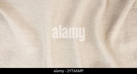 Nappe en lin avec plis à la lumière du soleil. Horizontal .Raped fond de tissu de lin beige brillant pour les fêtes de mariage et d'anniversaire dans le style boho. Vue de dessus avec espace pour le texte. Banque D'Images