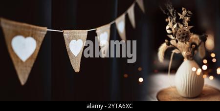 Chaîne de fête extérieure suspendue avec décoration florale dans le style boho et lumières dorées. Fond de nuit d'été pour mariage et vacances. Banque D'Images