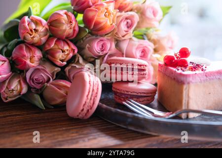 Beau bouquet de fleurs avec des délices sucrés. Forme de coeur, pâtisseries sucrées avec des roses roses et des tulipes sur table en bois. Fond pour la fête des mères et le mariage. Banque D'Images