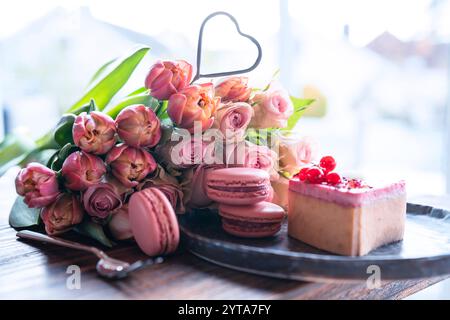 Beau bouquet de fleurs avec des délices sucrés. Forme de coeur, pâtisseries sucrées avec des roses roses et des tulipes sur table en bois. Fond pour la fête des mères et le mariage. Banque D'Images